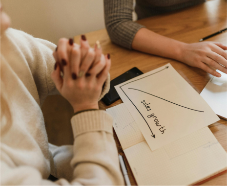 Professional discussing a handwritten sales growth chart during a strategy meeting.