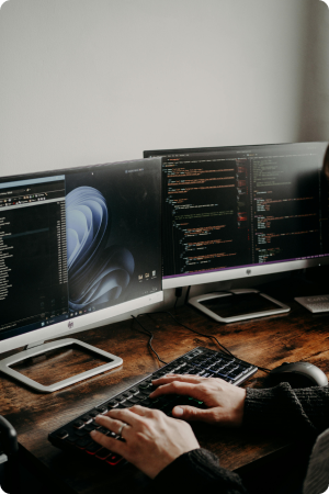 Developer using dual monitors for cloud DevOps coding and system optimization.