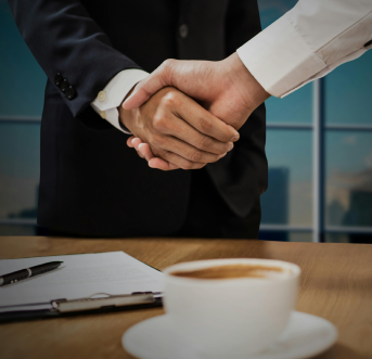 Professionals shaking hands after negotiating terms and confirming a job offer.
