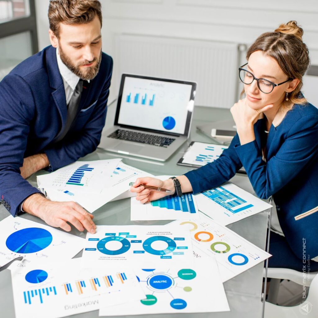 Two professionals discussing the analytics, reports and charts on a desk
