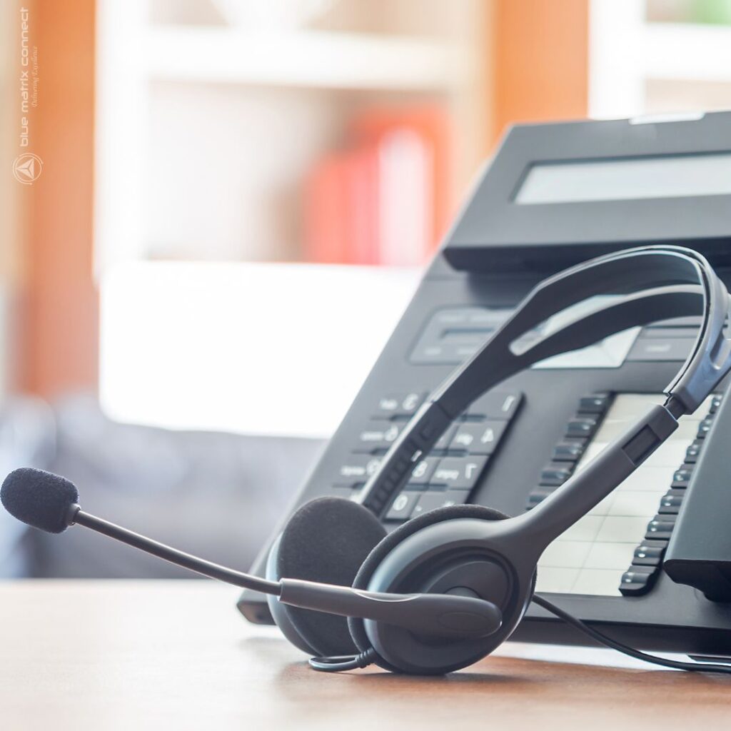 Headset resting on office phone and keyboard