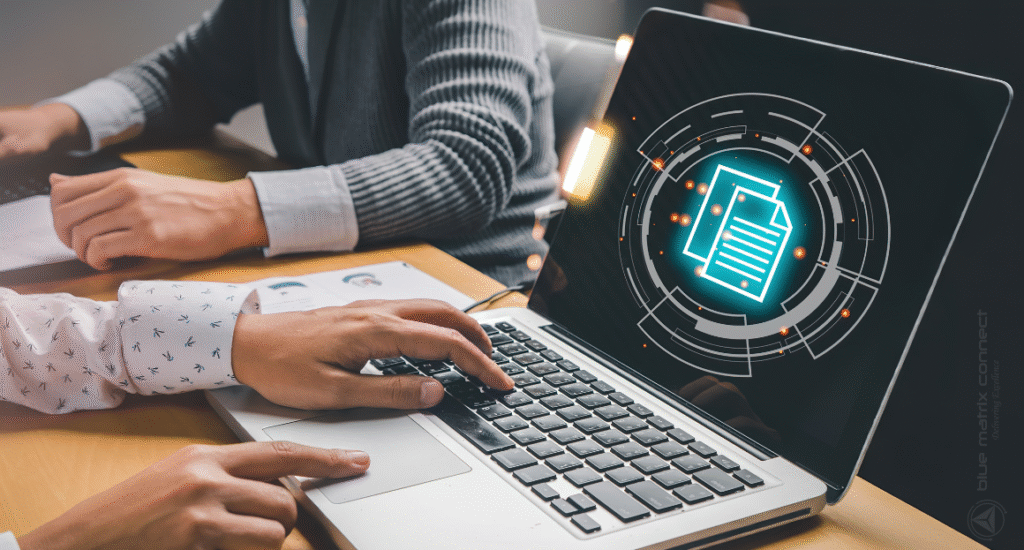 Two people working on a laptop, with a digital graphic of a document and data security icons appearing on the screen, symbolizing compliance checks and risk assessments.